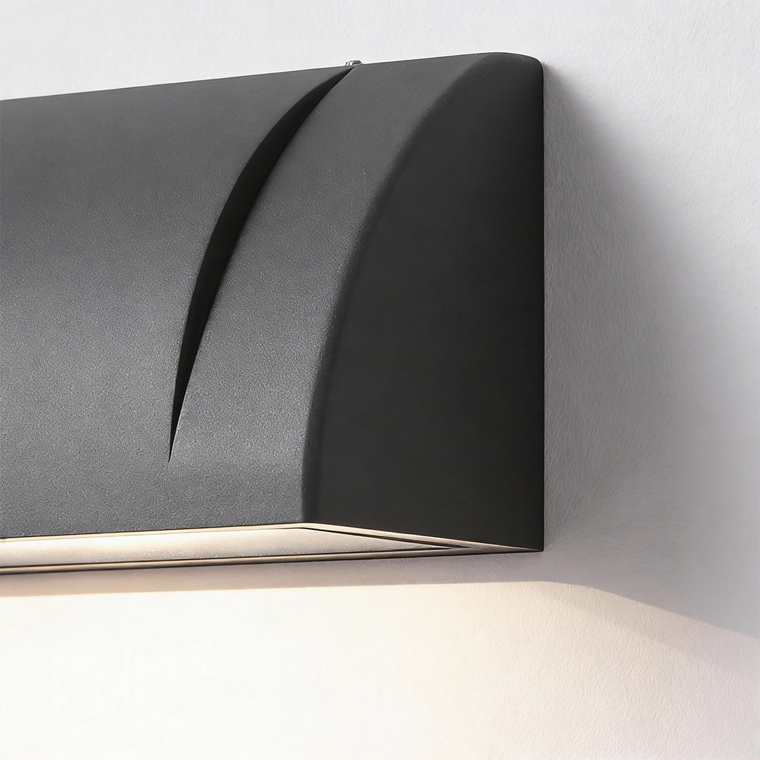 Down facing outdoor wall lights with a curved black metal housing, showing a close up front angle and soft downward illumination.