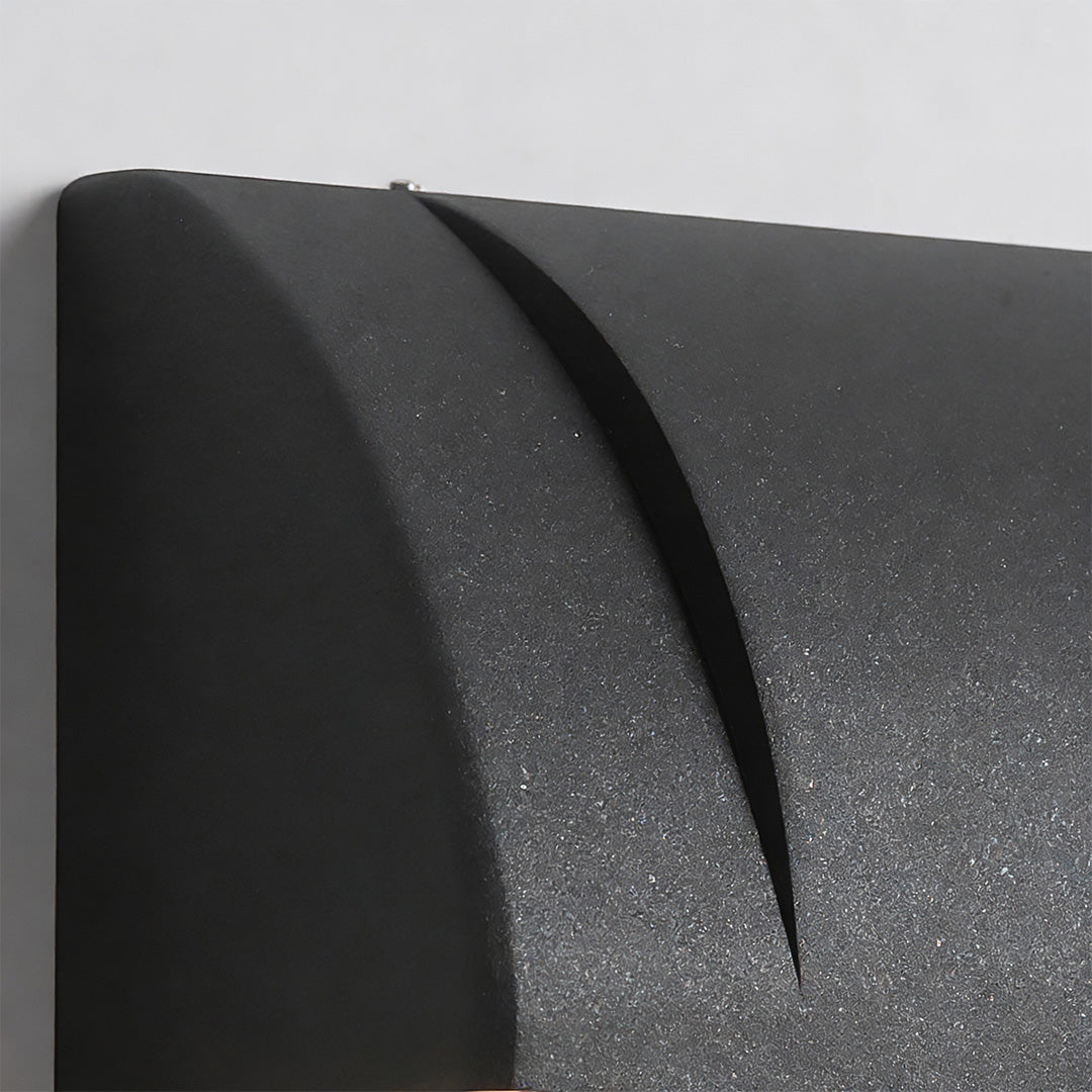 Down facing outdoor wall lights detail view highlighting the textured black finish and curved top design from a side angle.