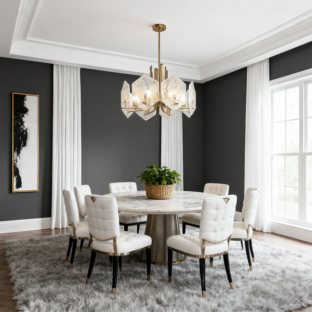 Dramatic dining room featuring a stunning gold geometric chandelier with faceted crystals over a round marble table.