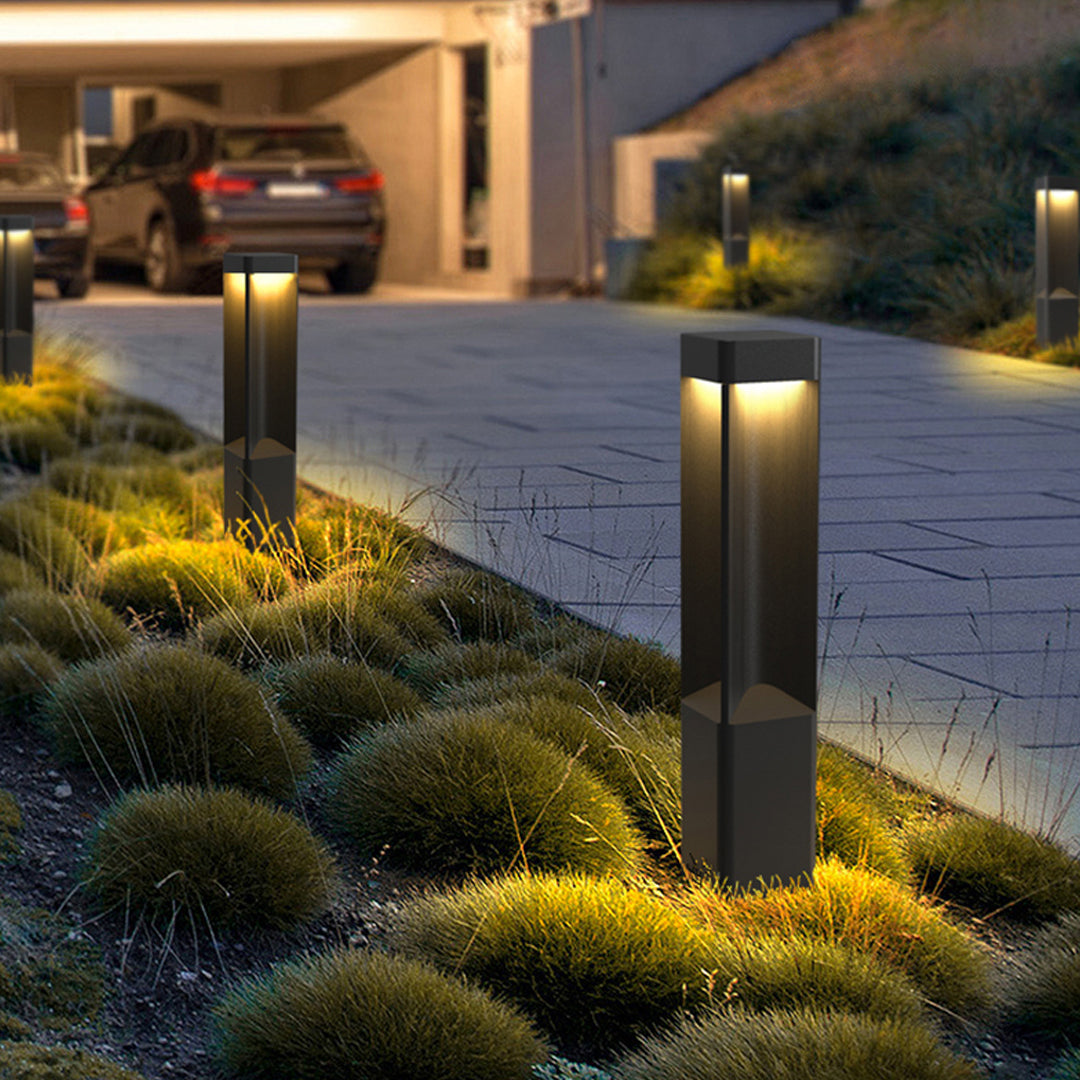 Contemporary driveway enhanced by tall bollards lighting fixtures producing warm directional light.