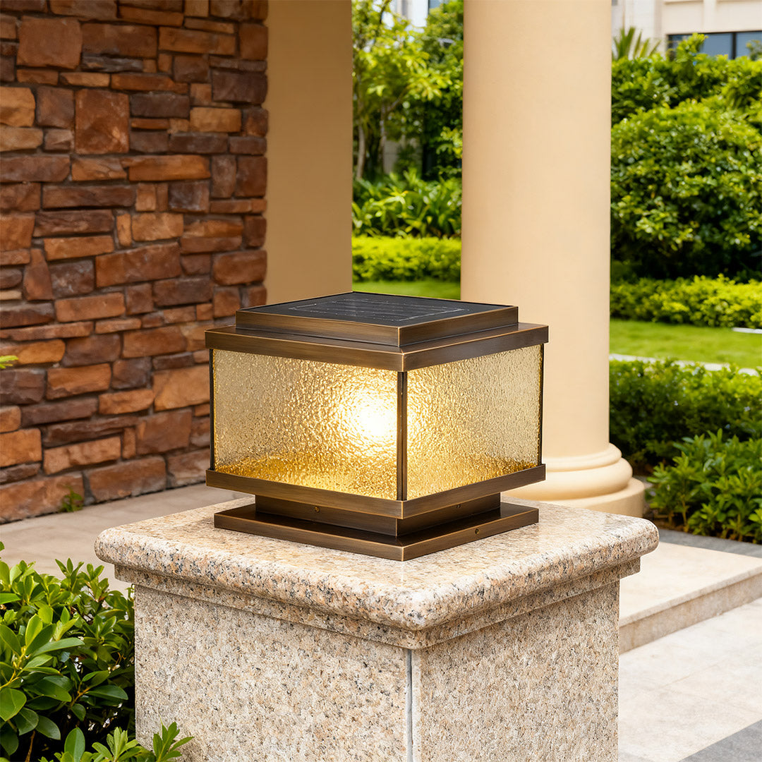 Pair of garden pillar lights mounted on gray concrete posts illuminating modern landscaped driveway
