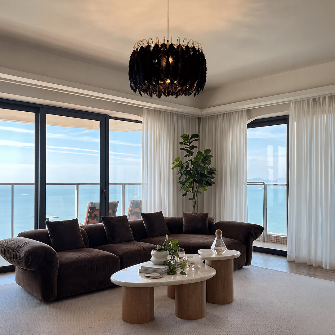 Black drum light chandelier hanging in a modern living room with floor-to-ceiling windows.