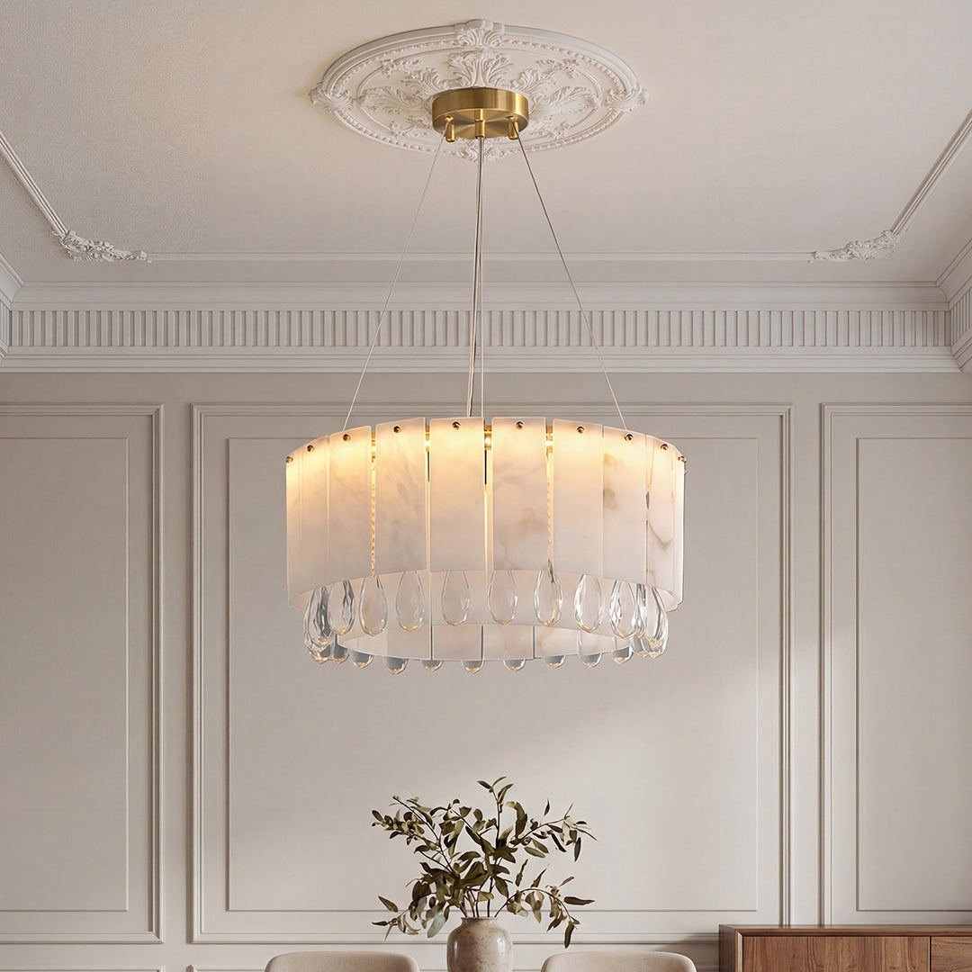 Stunning drum-shaped modern brass chandelier featuring faux alabaster panels and a bottom tier of clear crystal drops in an elegant room.