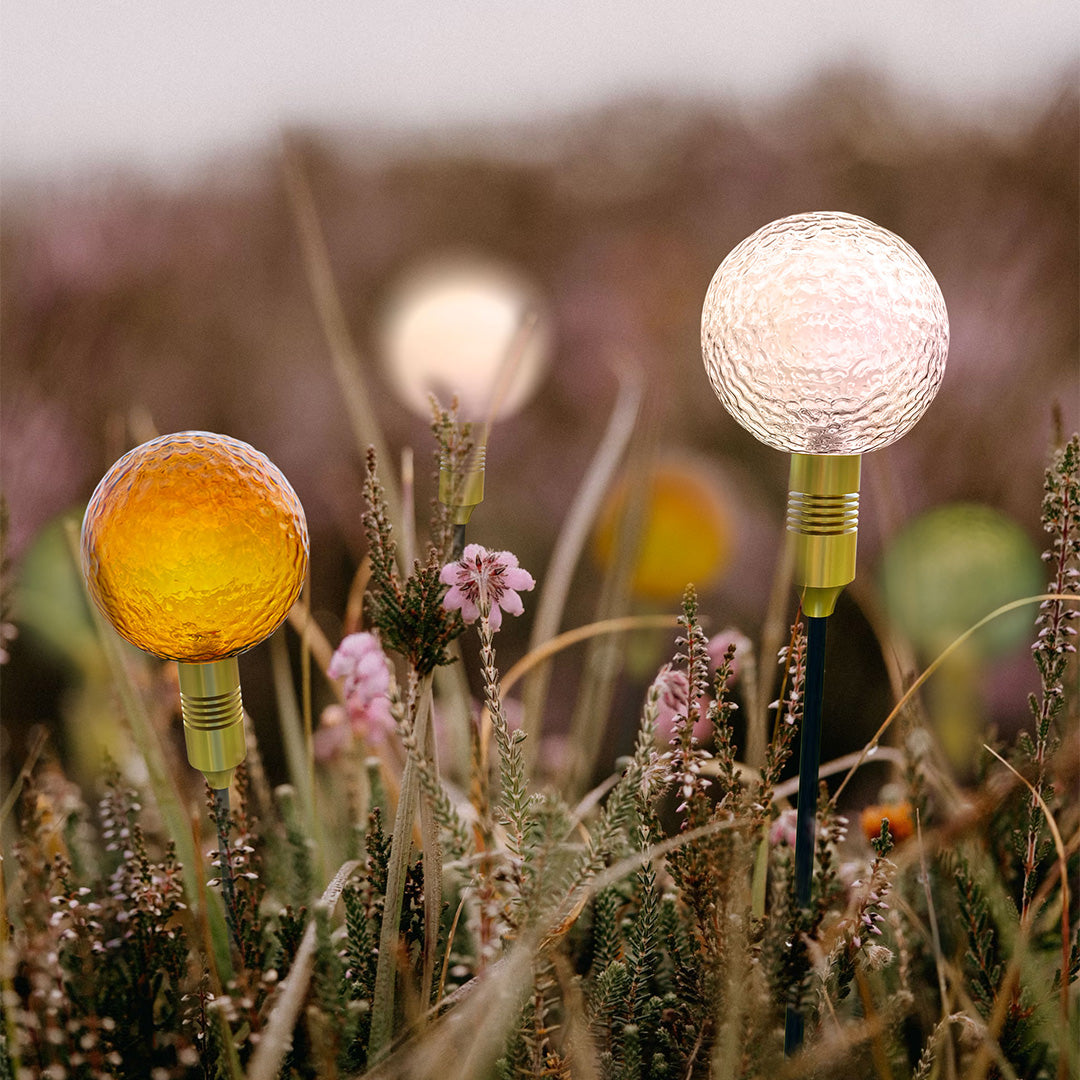 Cluster of crackle-glass globe lights glowing at dusk, enhancing outdoor path landscape lighting.