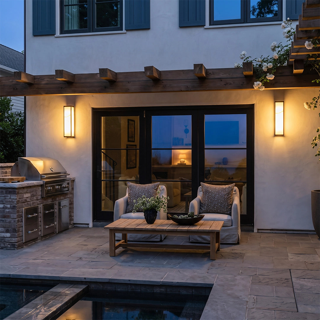 Econic outdoor wall lights installed beside a covered backyard patio, providing warm accent lighting near the seating and pool area.