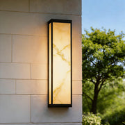 Econic outdoor wall light with a slim black frame and marble-look diffuser mounted on a stone exterior wall.