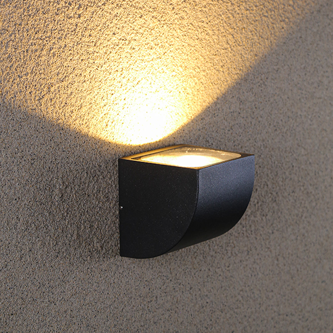 Traditional brass wall lantern with frosted glass shade mounted on stone exterior wall