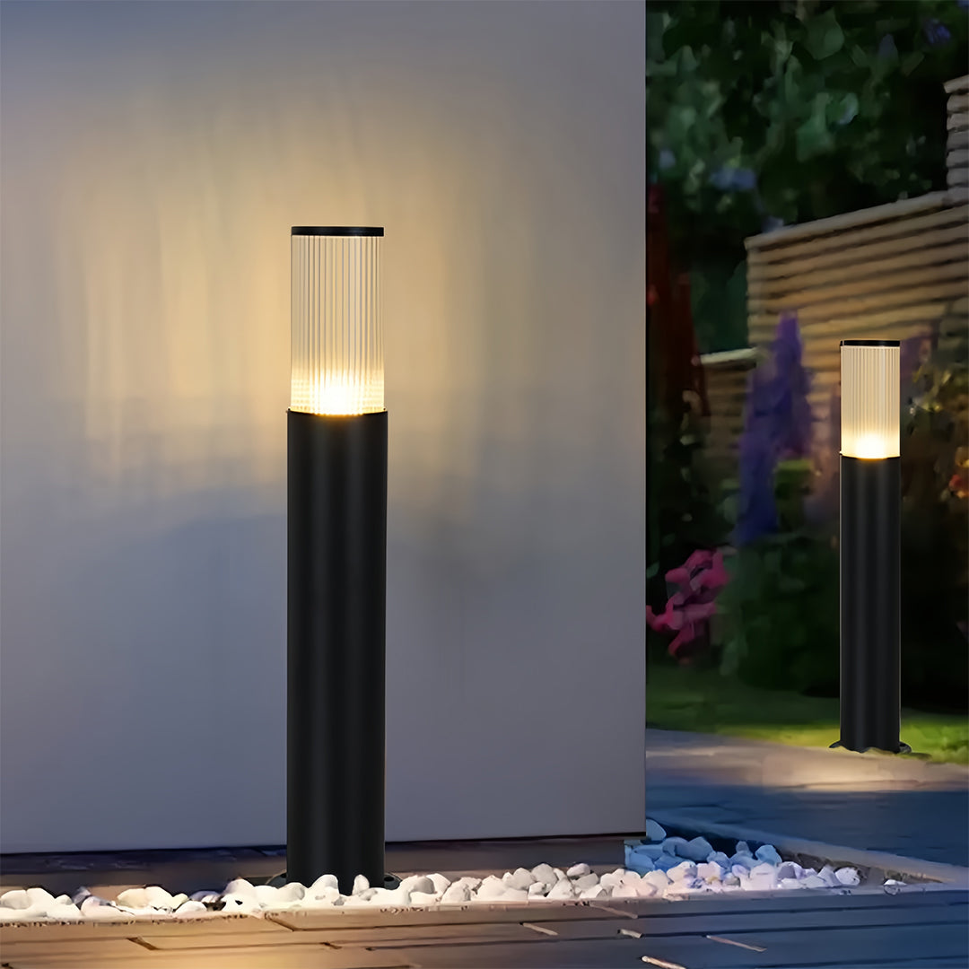 Elegant black bollard path light fixtures providing warm illumination against a home's exterior wall.