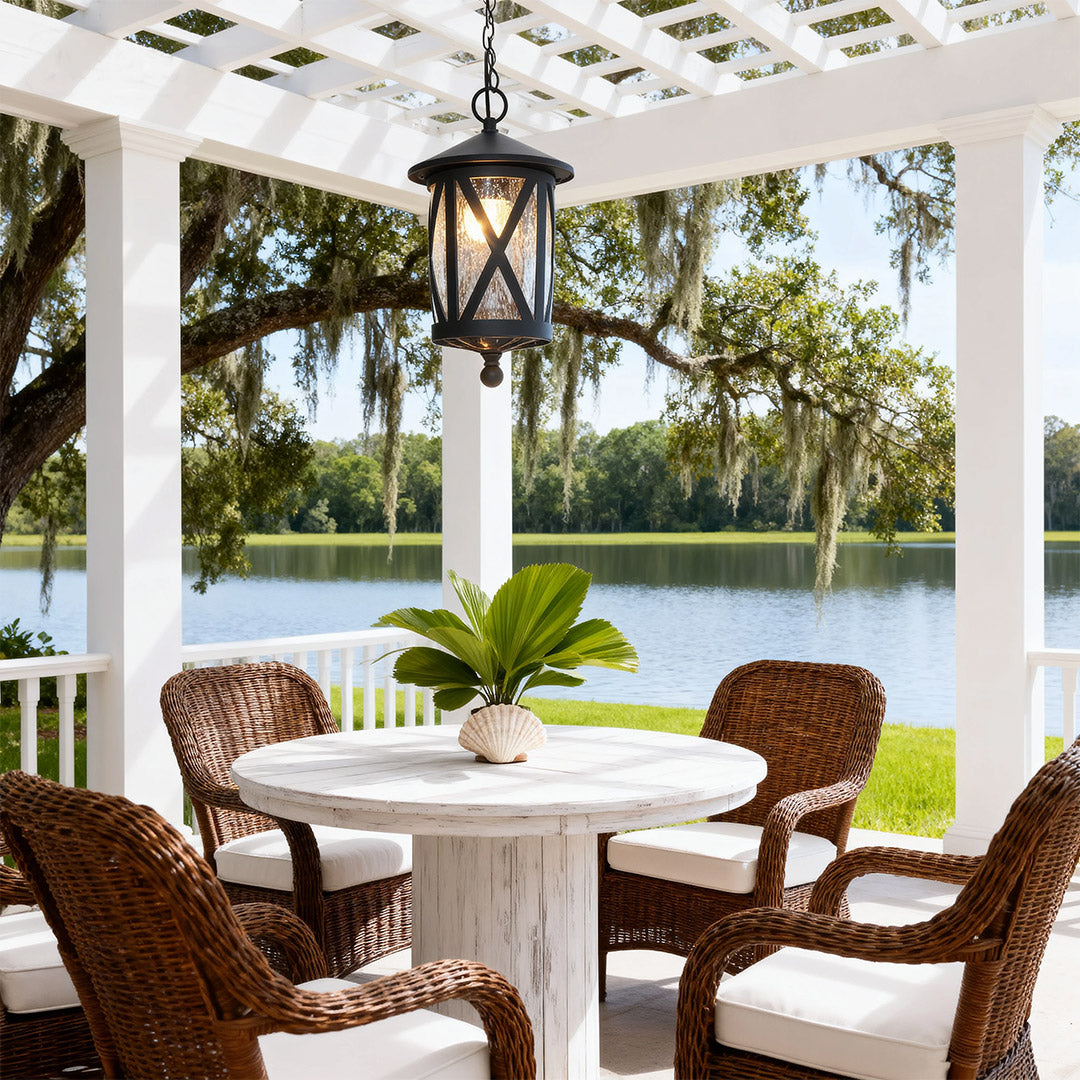 Elegant black outdoor pendant light hanging from white pergola over wicker furniture seating area