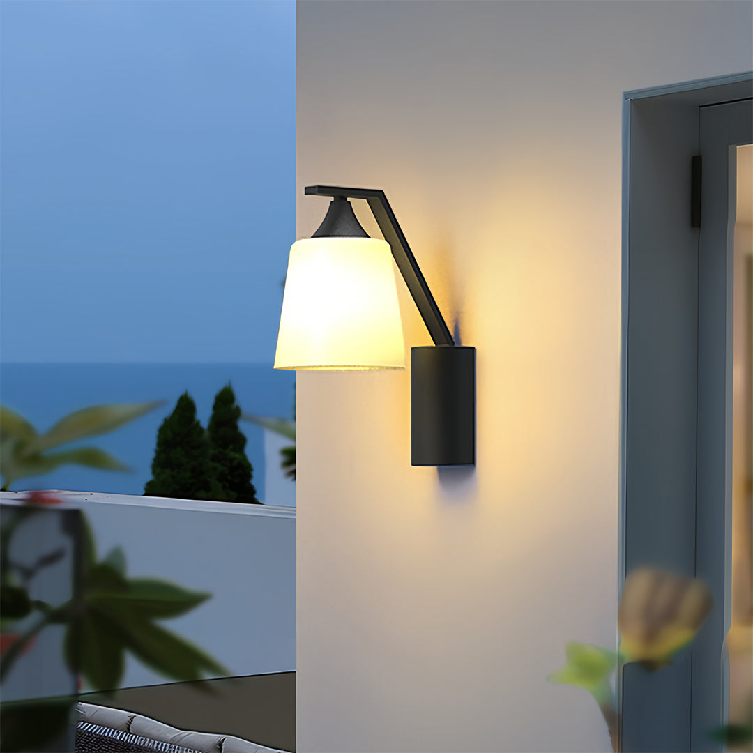 Stylish black outdoor sconce illuminating the exterior wall of a home, providing soft and elegant lighting at dusk.