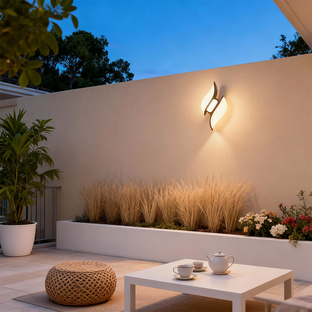 Elegant black outdoor wall sconces with glass shade chandelier design illuminating minimalist outdoor seating area at dusk.