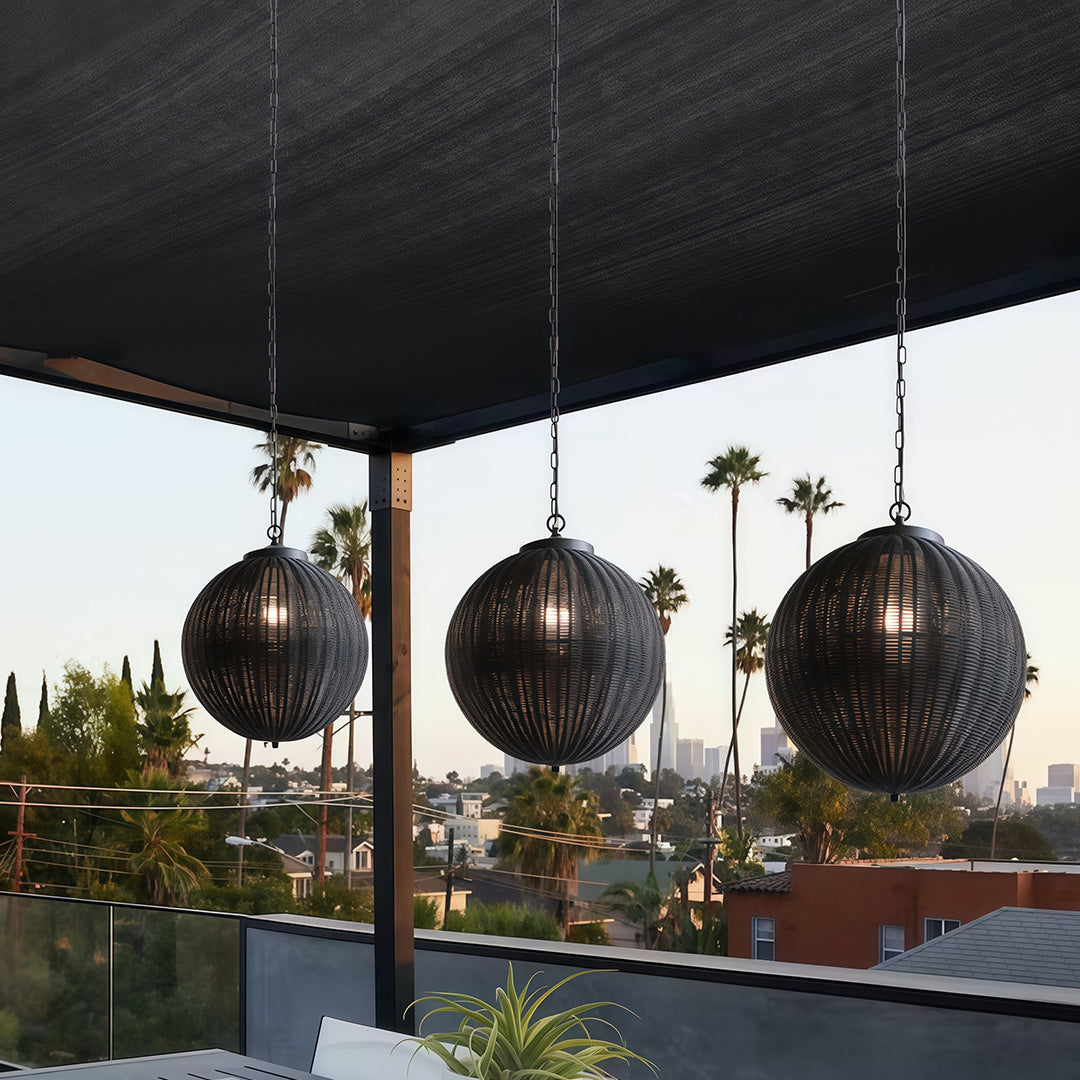 Elegant black woven pendant lights hanging over an outdoor dining space, providing ambient lighting at night.