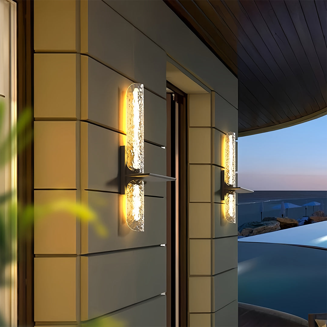 Elegant contemporary black outdoor wall lights casting a warm glow on patio pillars by a pool.