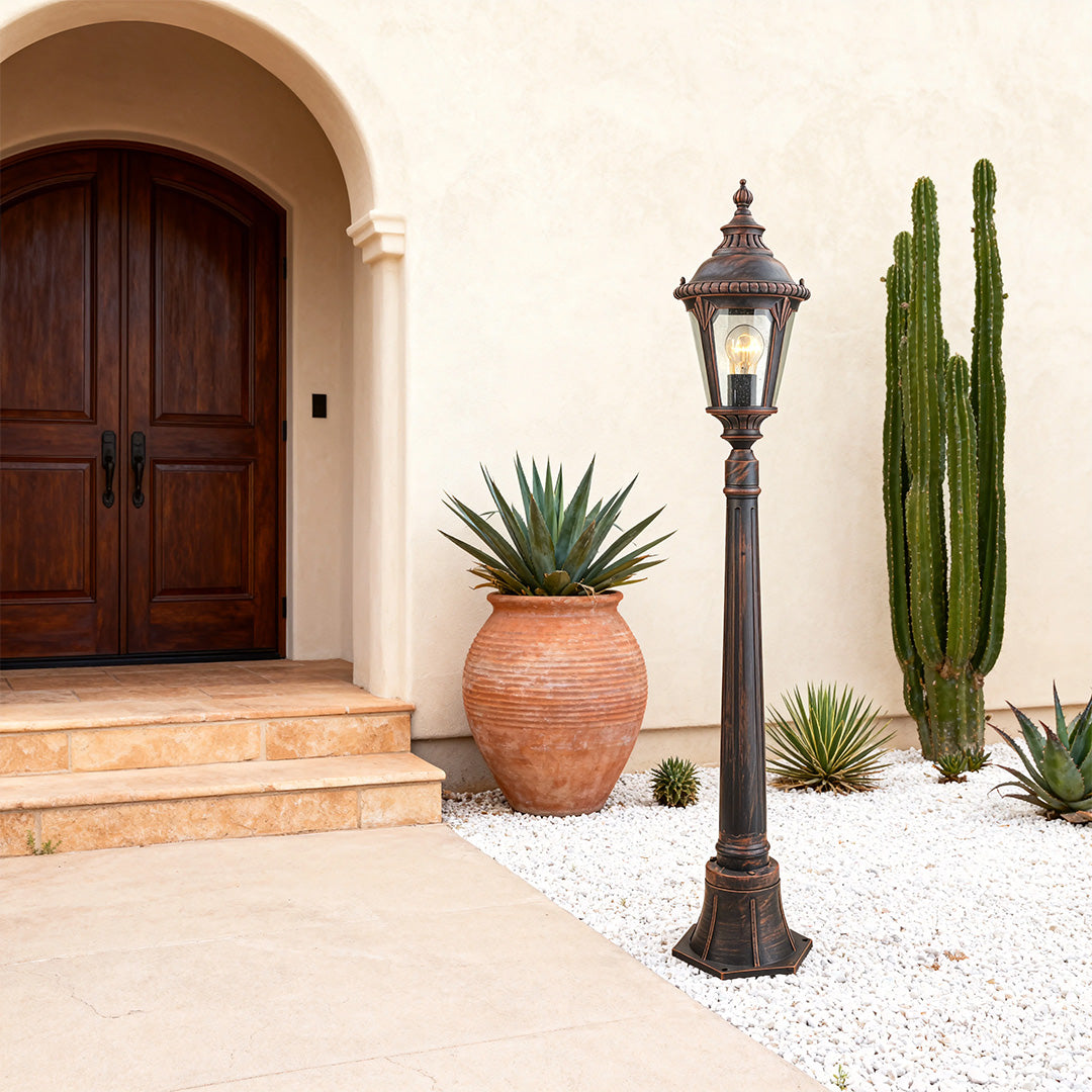 Elegant decorative bollard light positioned near arched doorway with white gravel and potted succulent