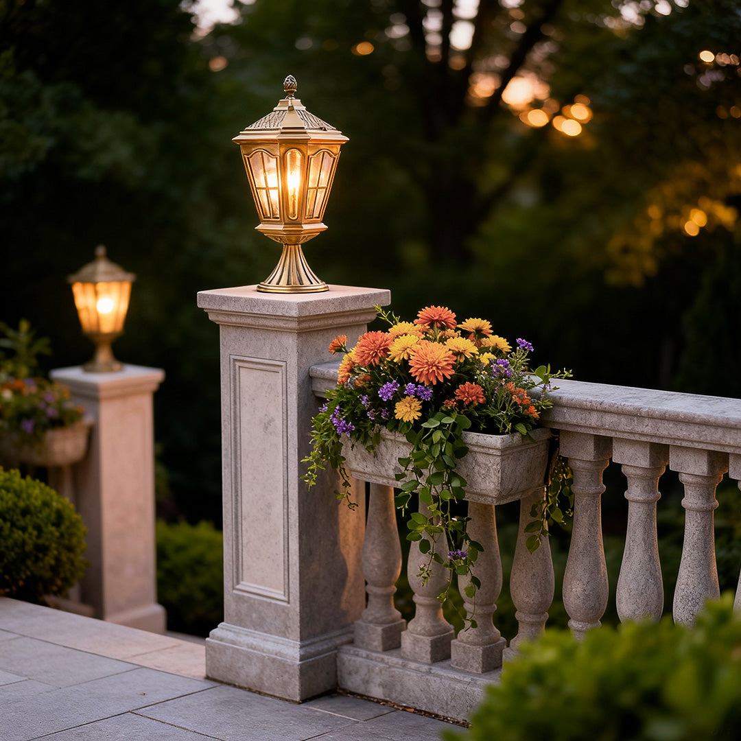Elegant exterior pillar mount lights illuminating a stone pillar beside a white picket fence.