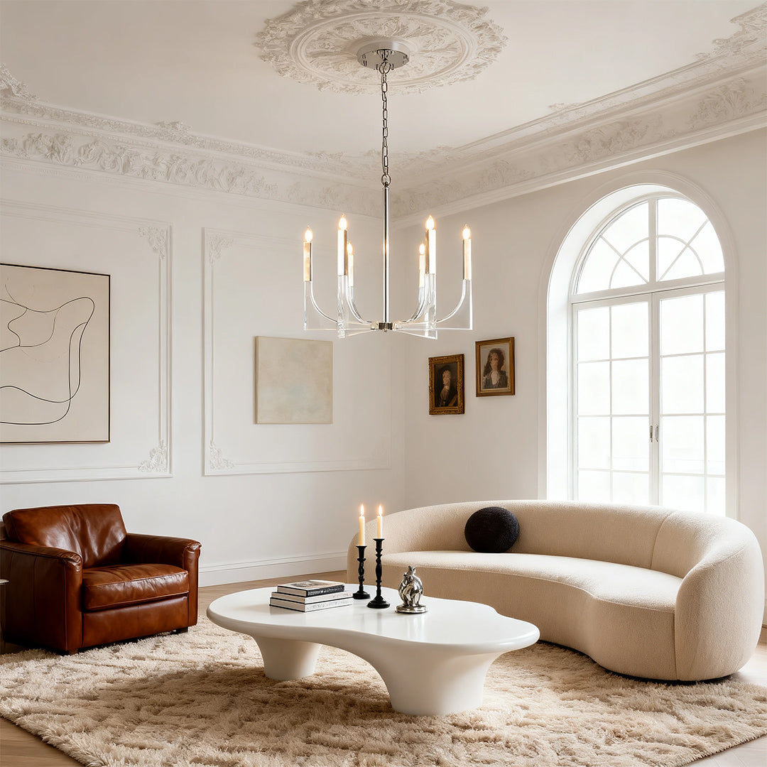 Elegant five-arm retro chandeliers over a sculptural white coffee table and plush curved sofa in a bright, arched-window living space.