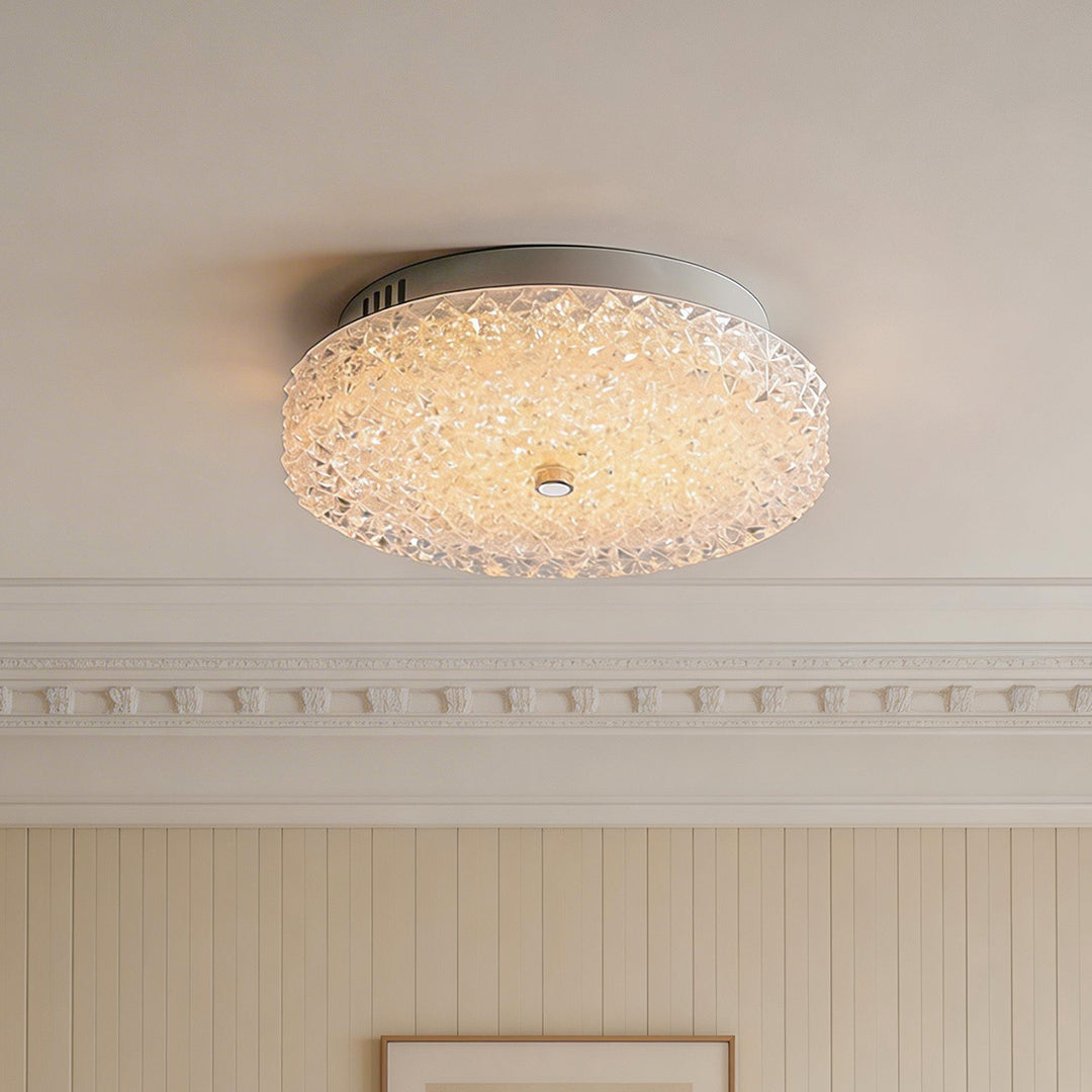Elegant flush mount crystal ceiling light glowing in a bright space with classic crown molding.