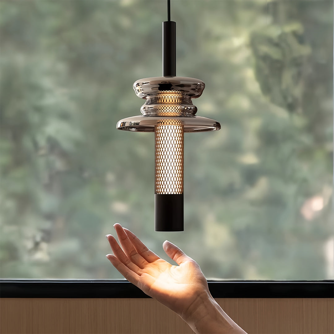 Elegant glass pendant lights featuring hand-held demonstration of textured bronze cylinder design