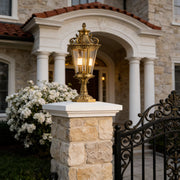 Elegant glass pillar lights mounted on stone pillars, enhancing the entrance of a luxurious home with warm lighting.
