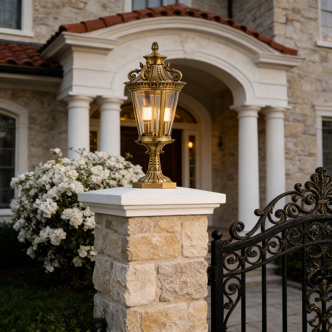 Elegant glass pillar lights mounted on stone pillars, enhancing the entrance of a luxurious home with warm lighting.
