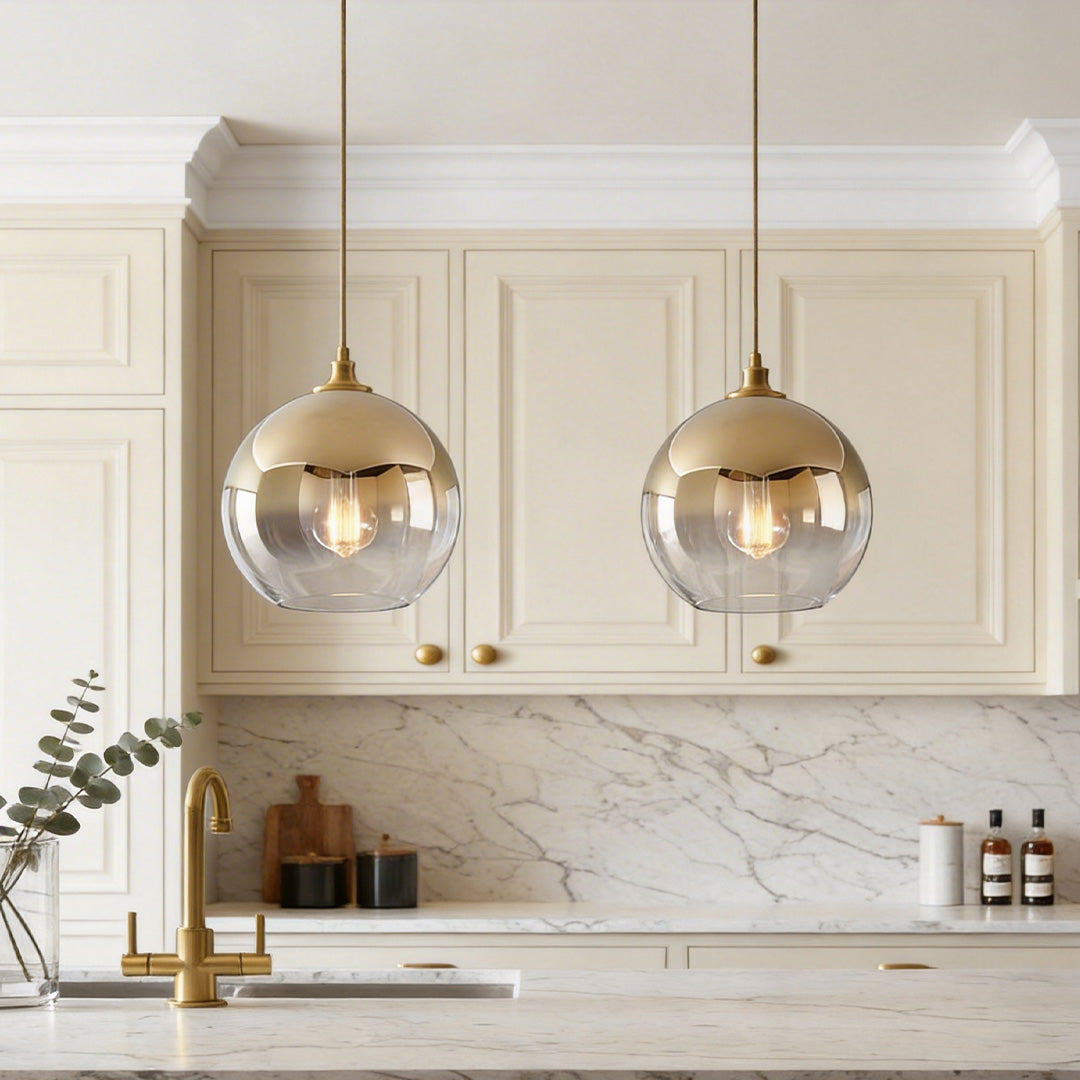 Elegant glass round pendant light with a brass top half hanging over a classic kitchen island.