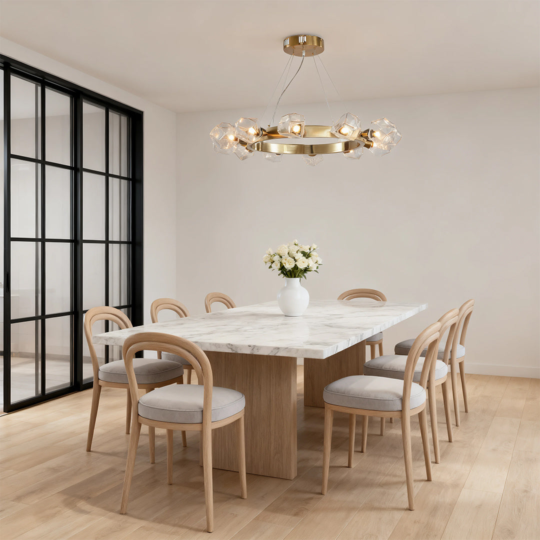 Bright, airy dining area featuring an elegant gold round chandelier with multiple clear glass spheres above a long wooden table.
