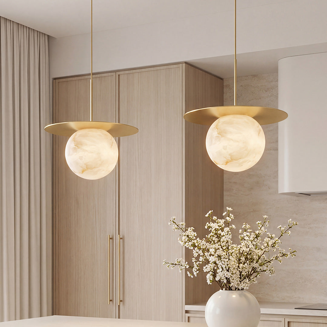 Elegant ball pendant lights with gold discs and marble patterned globes in a modern kitchen.