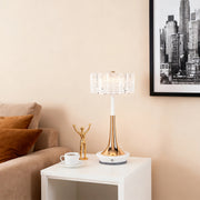 Elegant gold-finish cordless mushroom table lamp with a crystal shade on a white side table next to a sofa. 