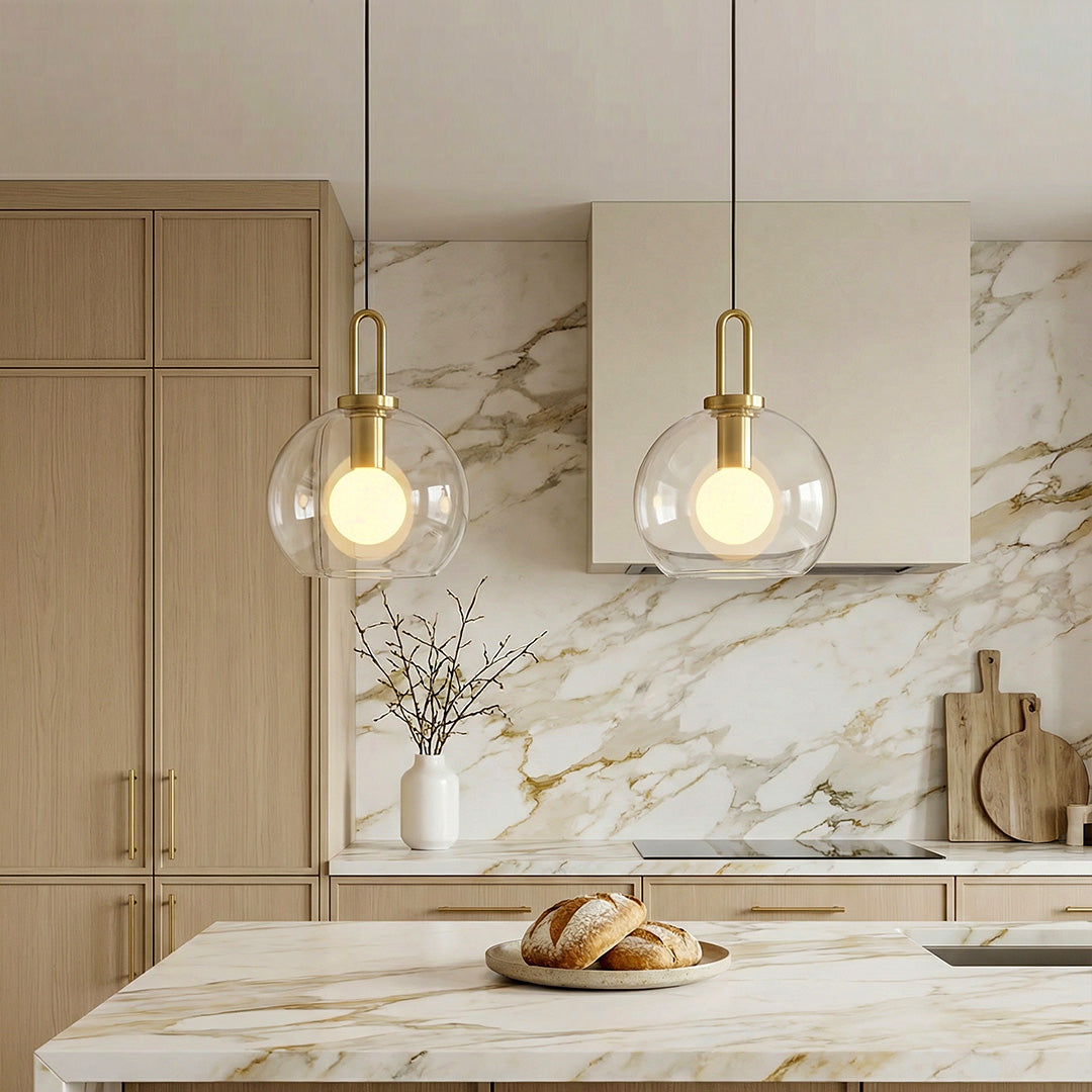 Elegant frosted glass mini pendant lights with gold U-loop hardware in a luxury marble kitchen.