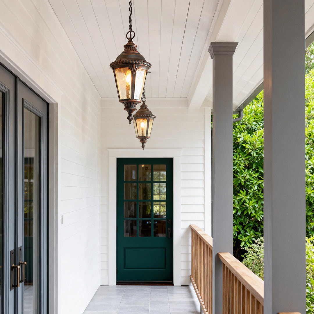 Elegant industrial pendant light suspended from white porch ceiling near black door and railing