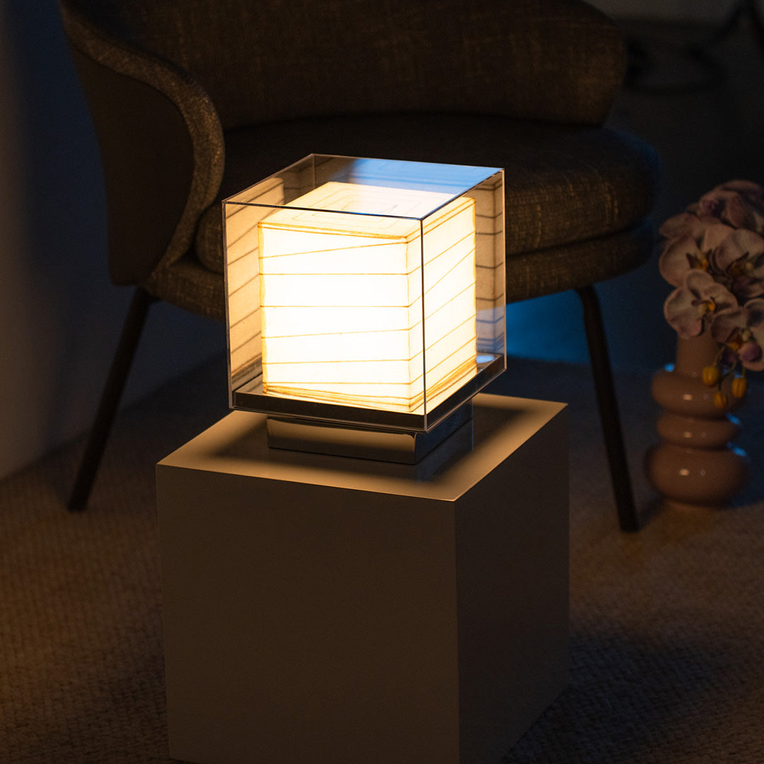 Elegant Japanese paper table lamp on a modern stand, radiating peaceful light.