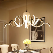 Elegant LED ribbon chandelier hanging above a dining table, adding modern sophistication to a warm-toned room.