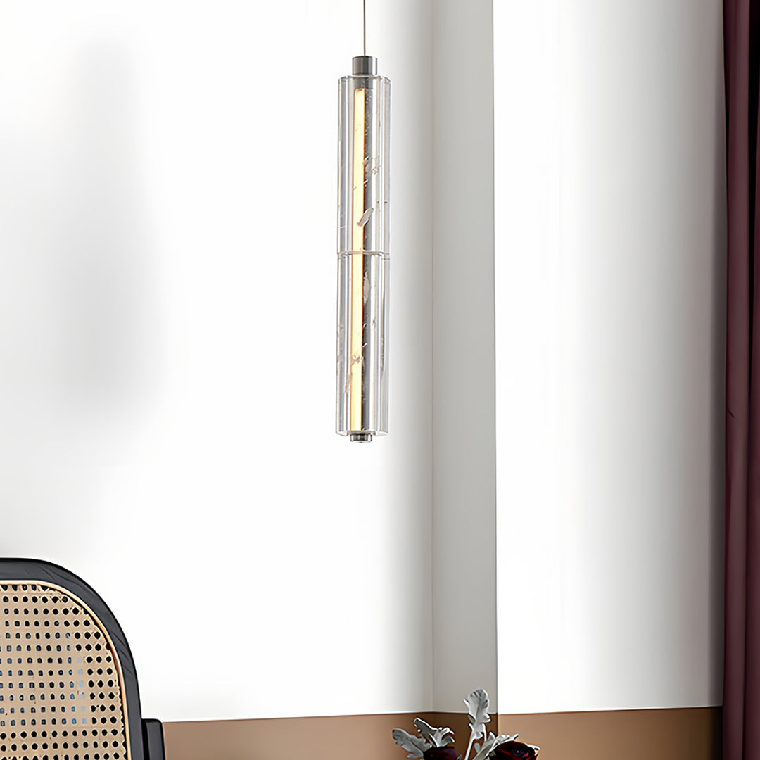 Elegant modern crystal pendant light illuminating a cozy corner with a chair and side table.