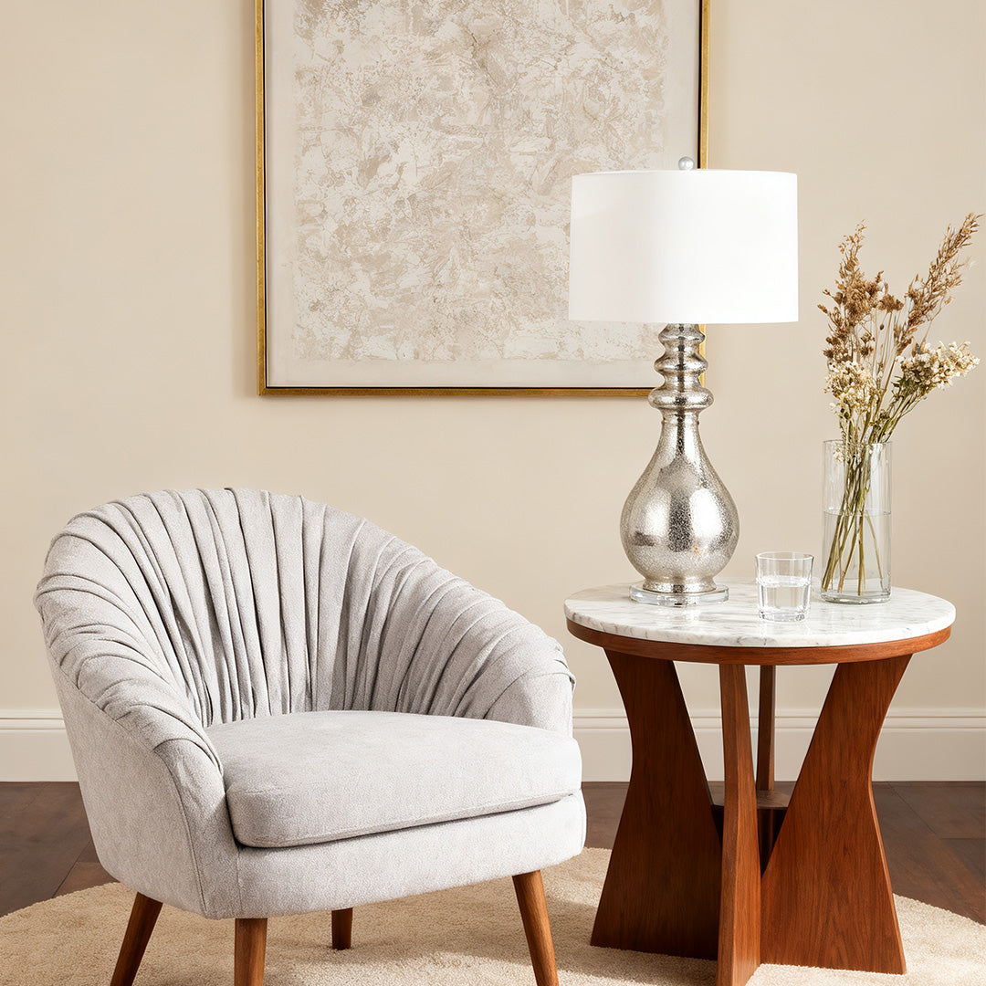 Elegant modern silver table lamp on a marble side table next to a comfortable upholstered armchair in a cozy reading nook.