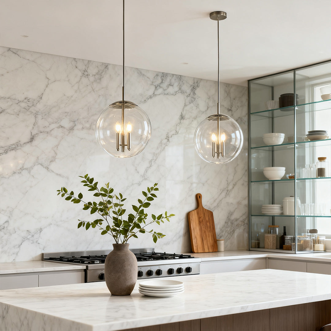 Single elegant glass orb pendant light with polished nickel hardware over a bright white kitchen island with marble backsplash.