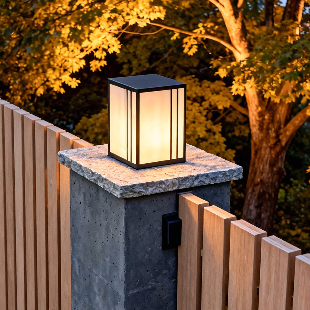Elegant outdoor pillar lights LED adding ambiance to a modern fence and stone pillar at night.