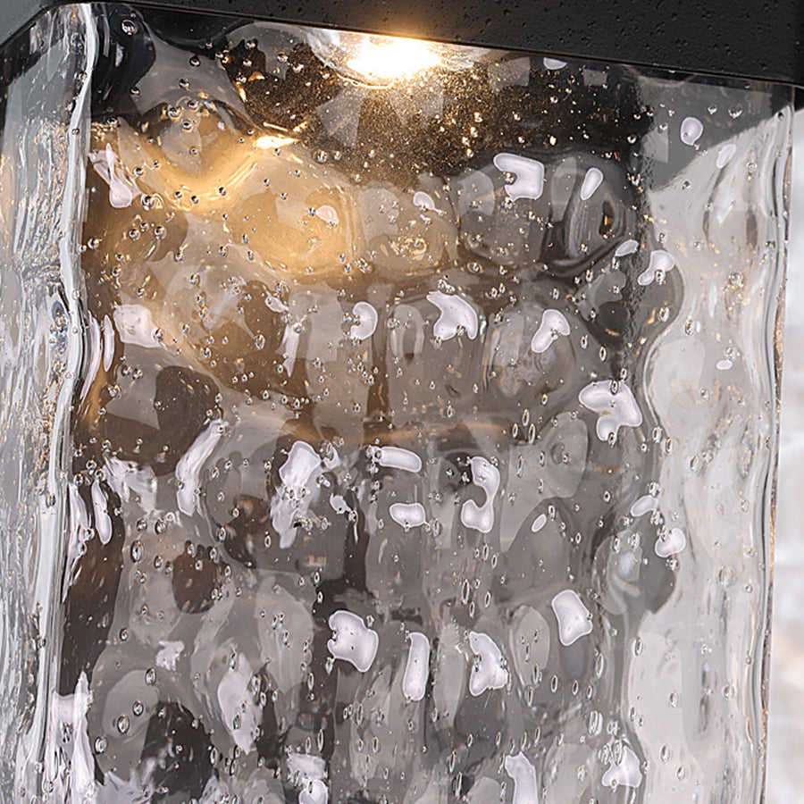 Elegant outdoor light fixture with textured glass creating warm glow on natural stone wall