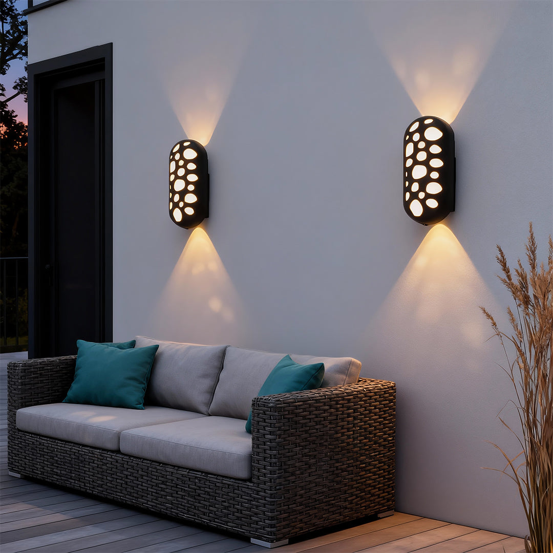 Elegant paired outdoor up down wall lights with glass shade chandelier design illuminating contemporary outdoor seating area at dusk.