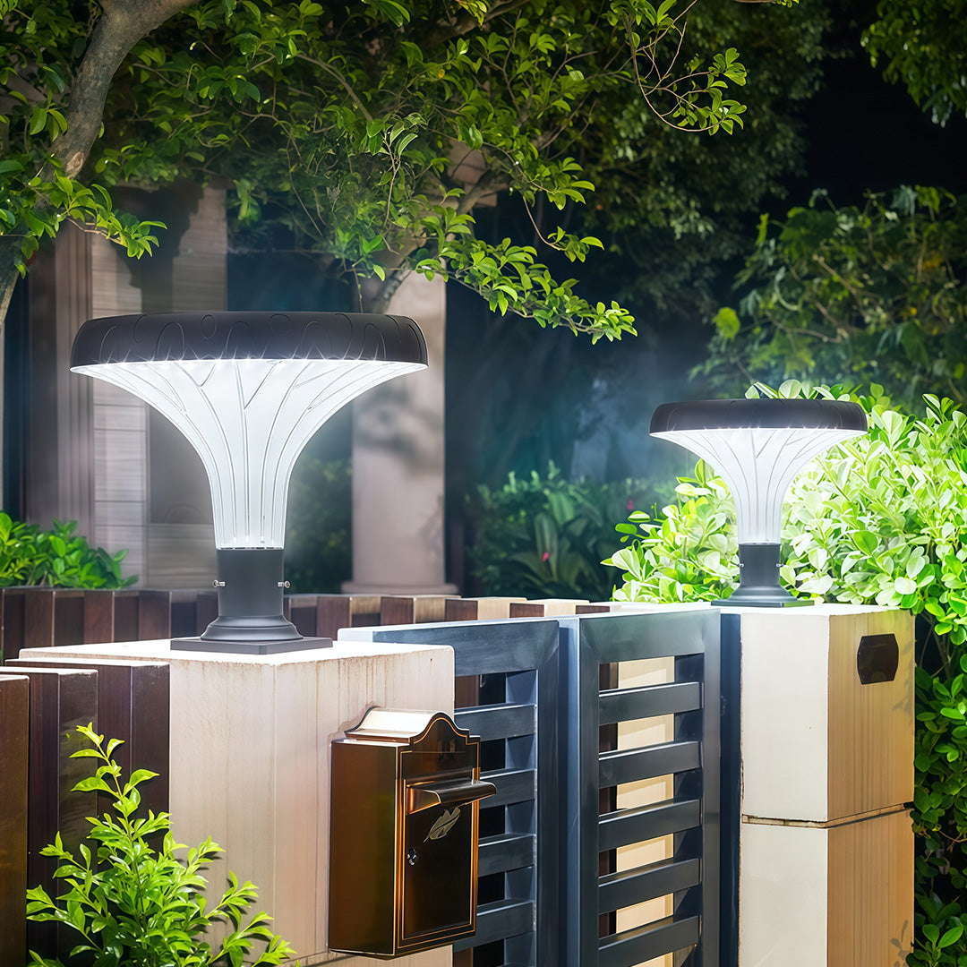 Elegant pillar light brightening the area around a residential garden fence at night.