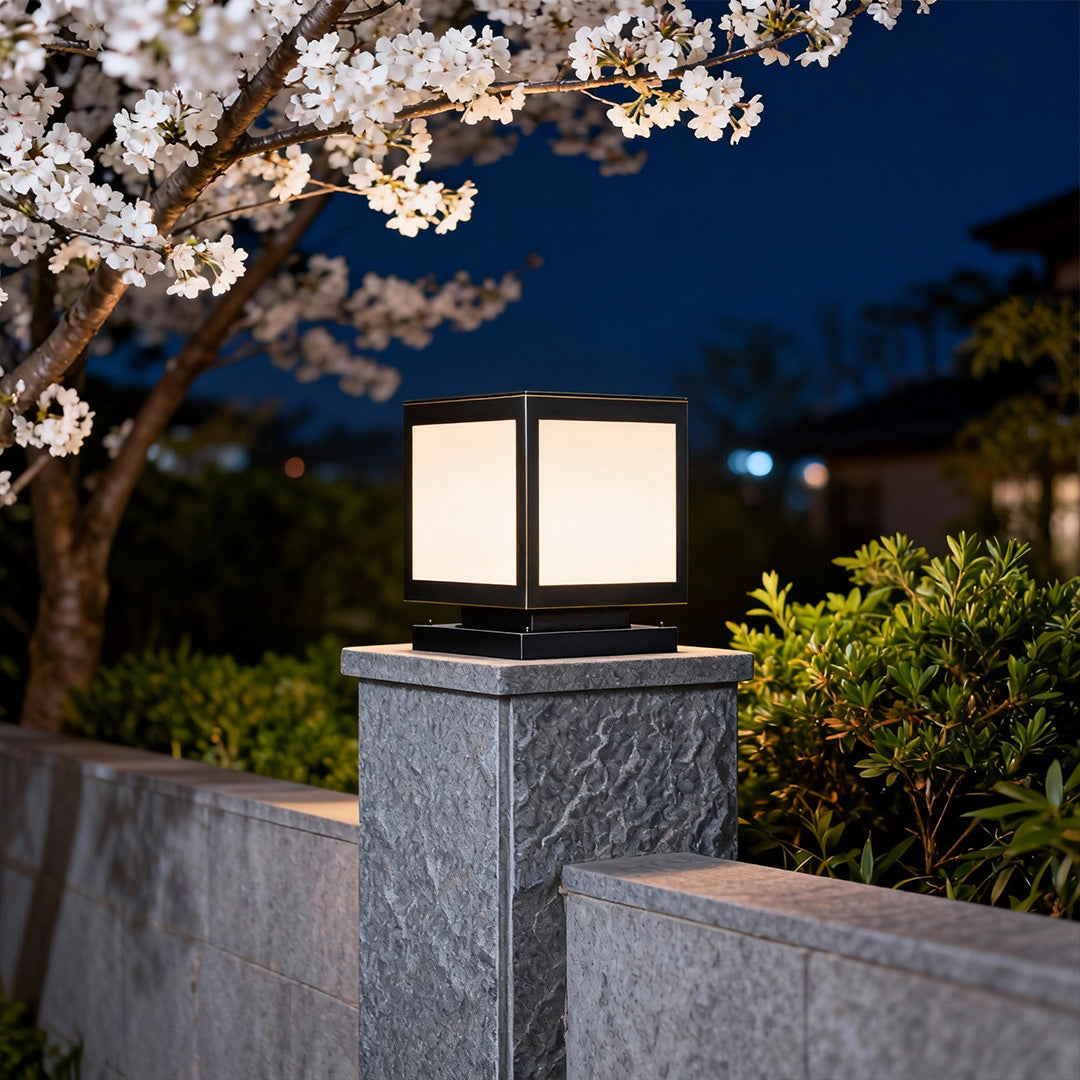 Elegant pillar solar light glowing softly on a stone pillar with blooming flowers in the background.