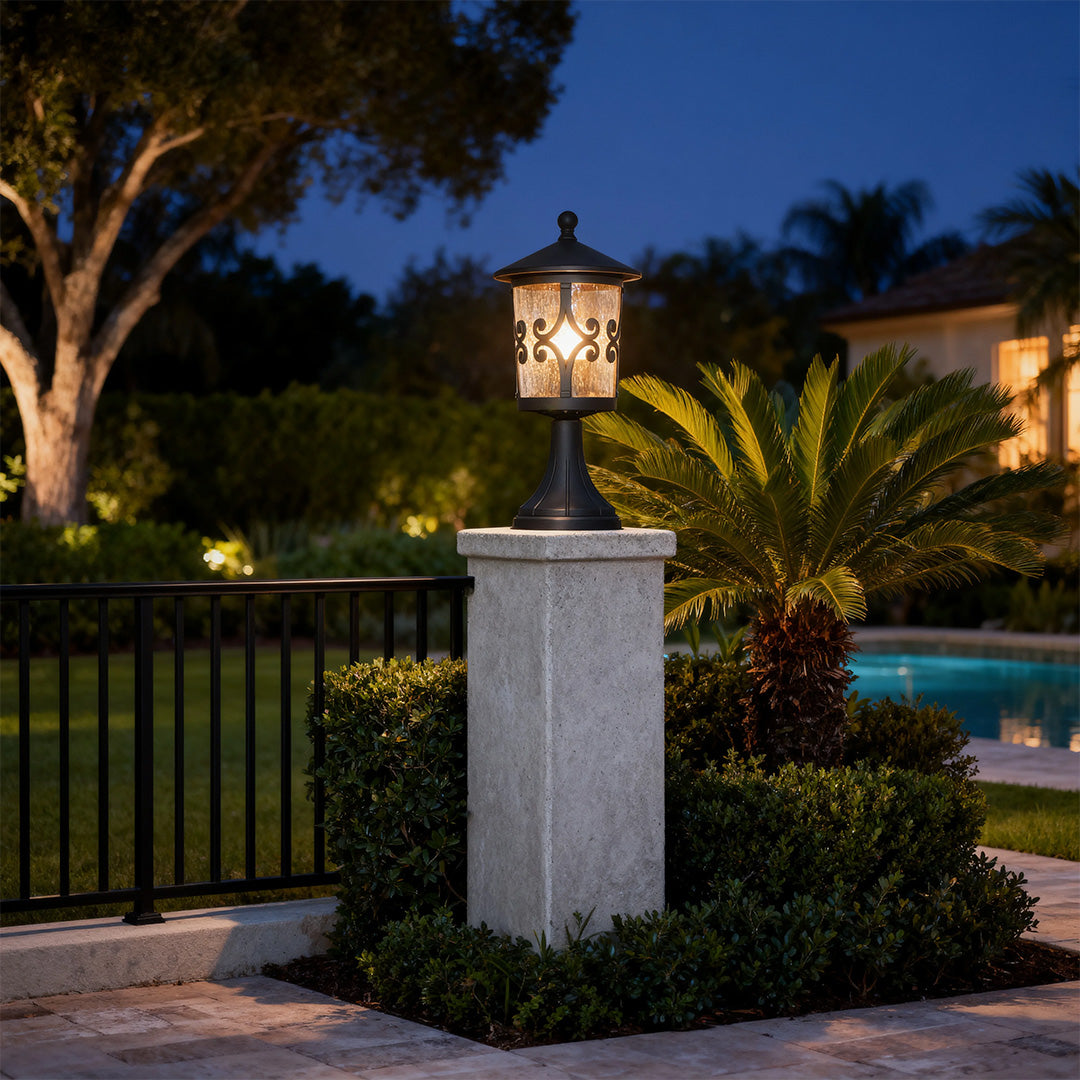 Elegant porch pillar light casting warm illumination on textured column near palm landscaping at evening