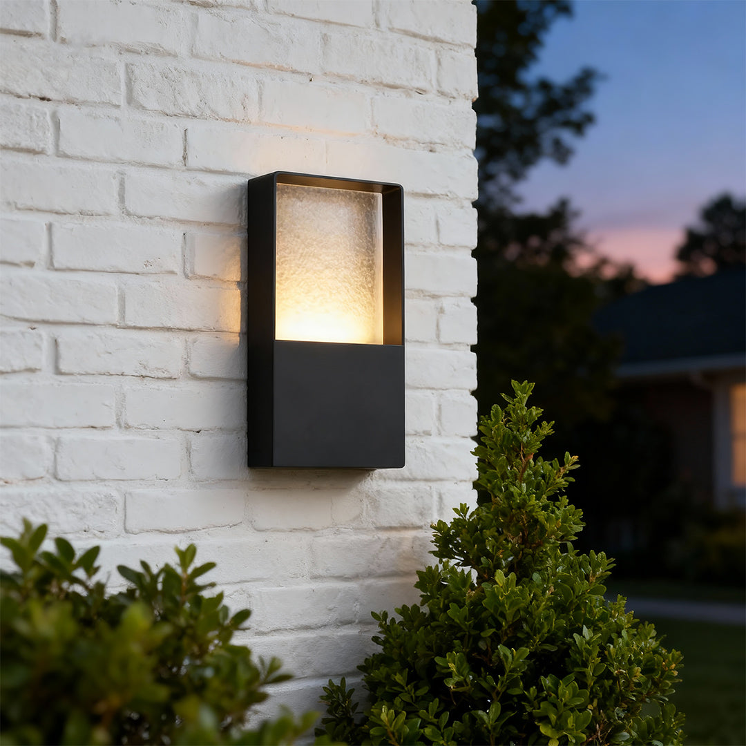 Elegant rectangular wall mount exterior light featuring glass shade chandelier styling on white brick exterior at twilight.