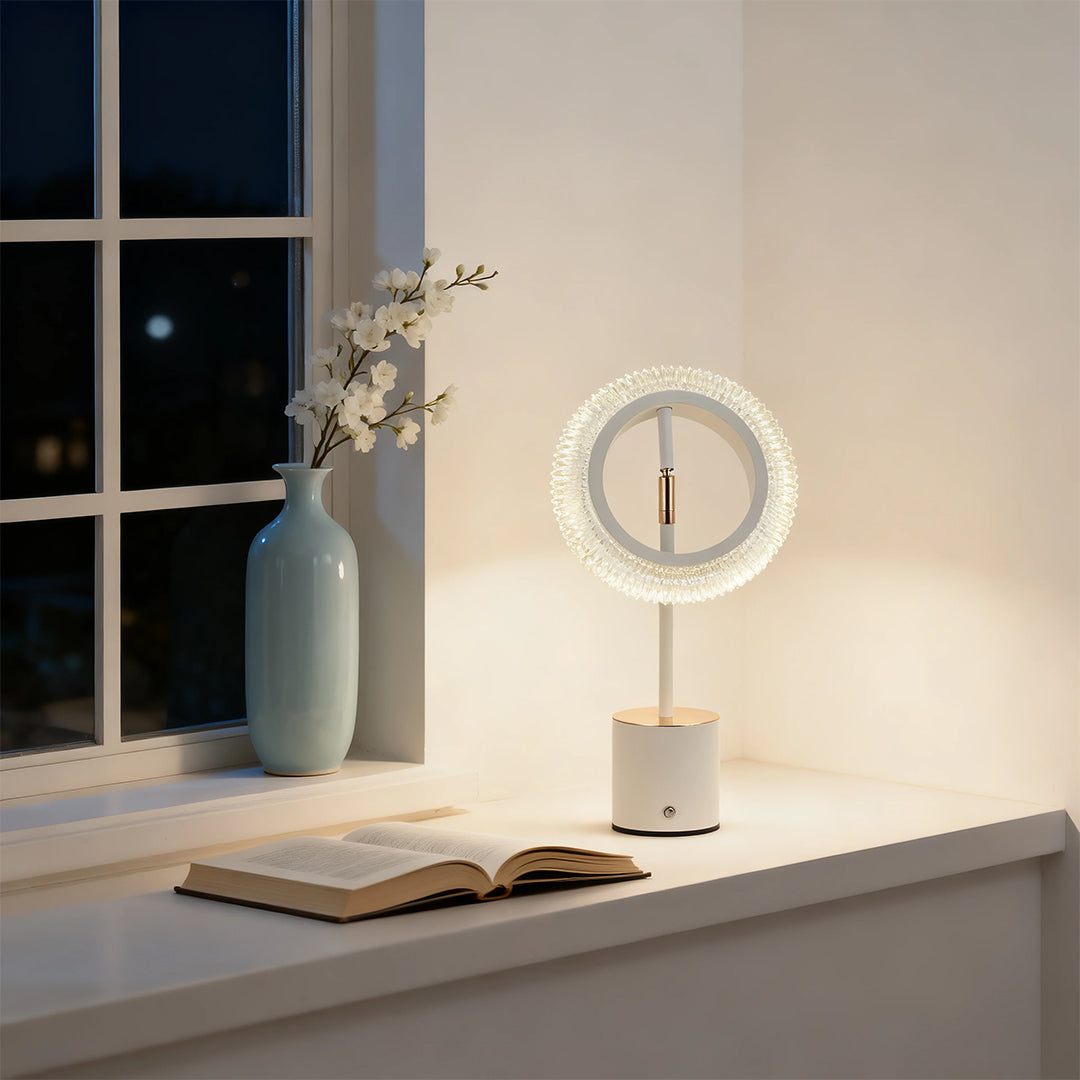 Elegant ring table lamp providing soft illumination for reading by a window at night in a clean interior.