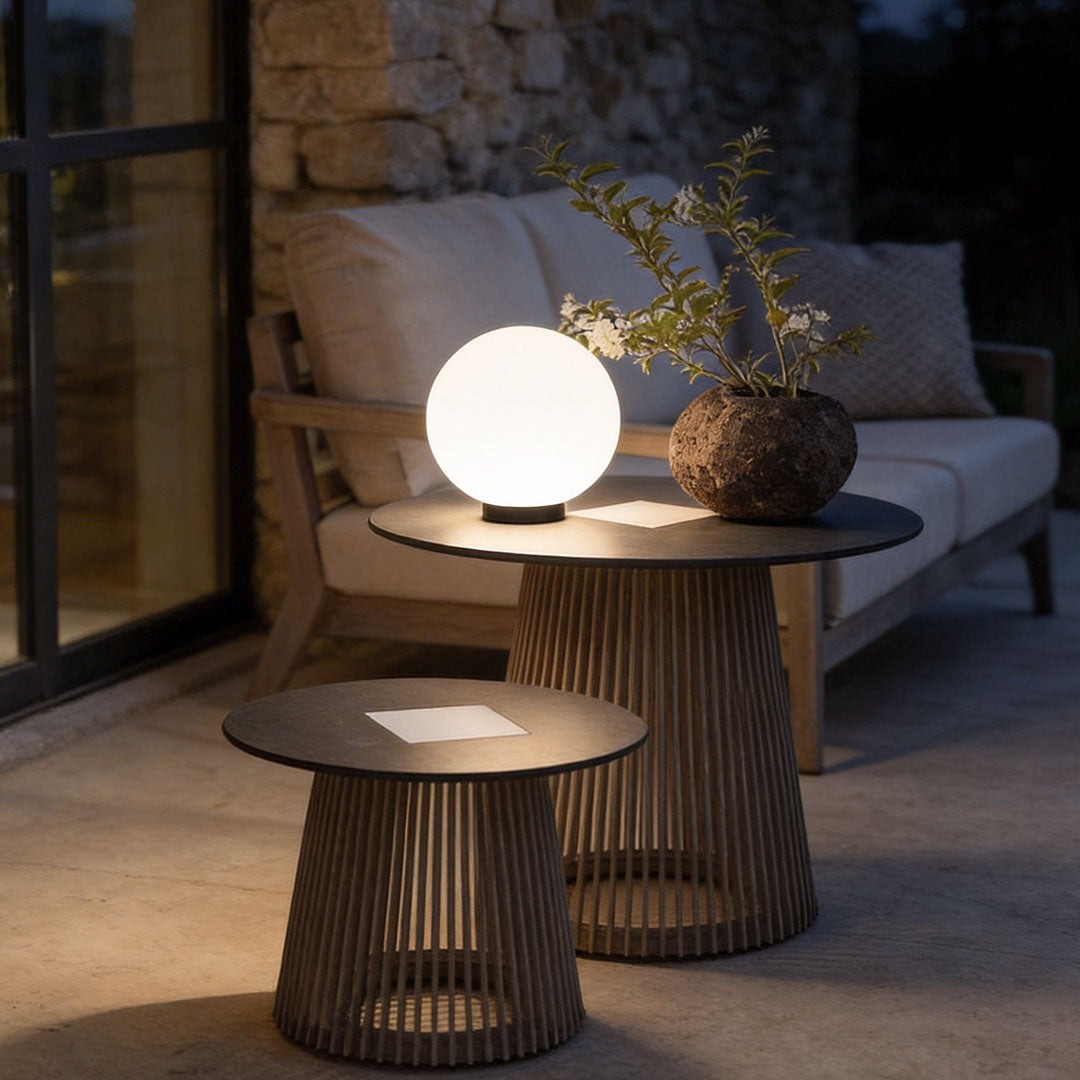 Elegant round landscape lighting globe on a modern slatted side table for cozy outdoor decor.