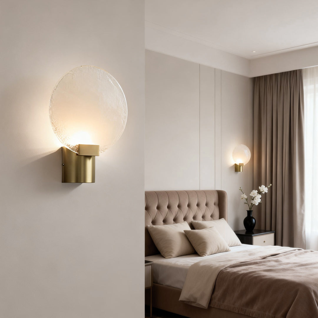 Elegant round wall light with a frosted glass shade and gold base, illuminating a minimalist bedroom nightstand.