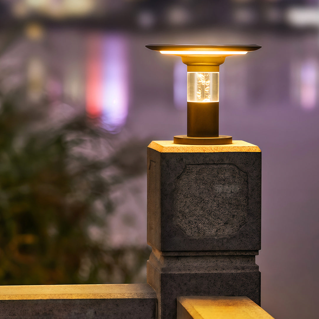 Elegant solar post cap light with bubble glass casting a warm glow on a stone pillar at night.