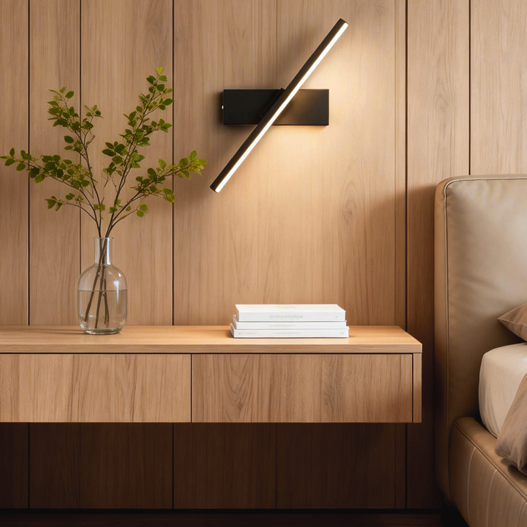 Elegant swivel wall light featuring a black frame and warm light, paired with a potted plant on a wooden side table.