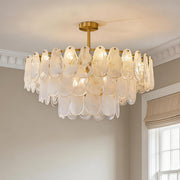 Elegant tiered midcentury modern chandelier featuring textured frosted glass pendants and a gold finish in a bright room.