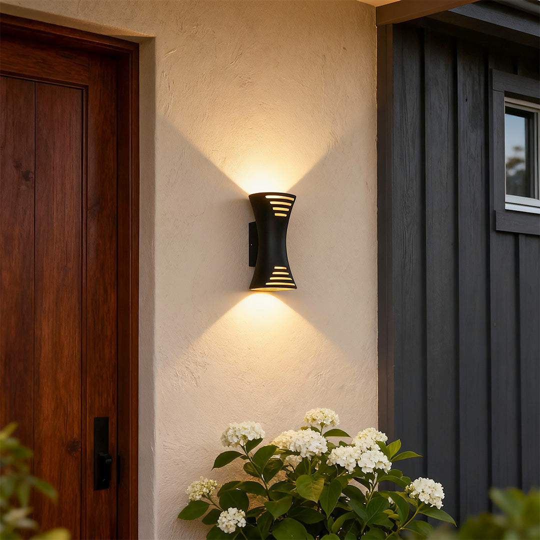 Elegant up down lighting wall sconce with glass shade chandelier design illuminating traditional exterior beside wood door.