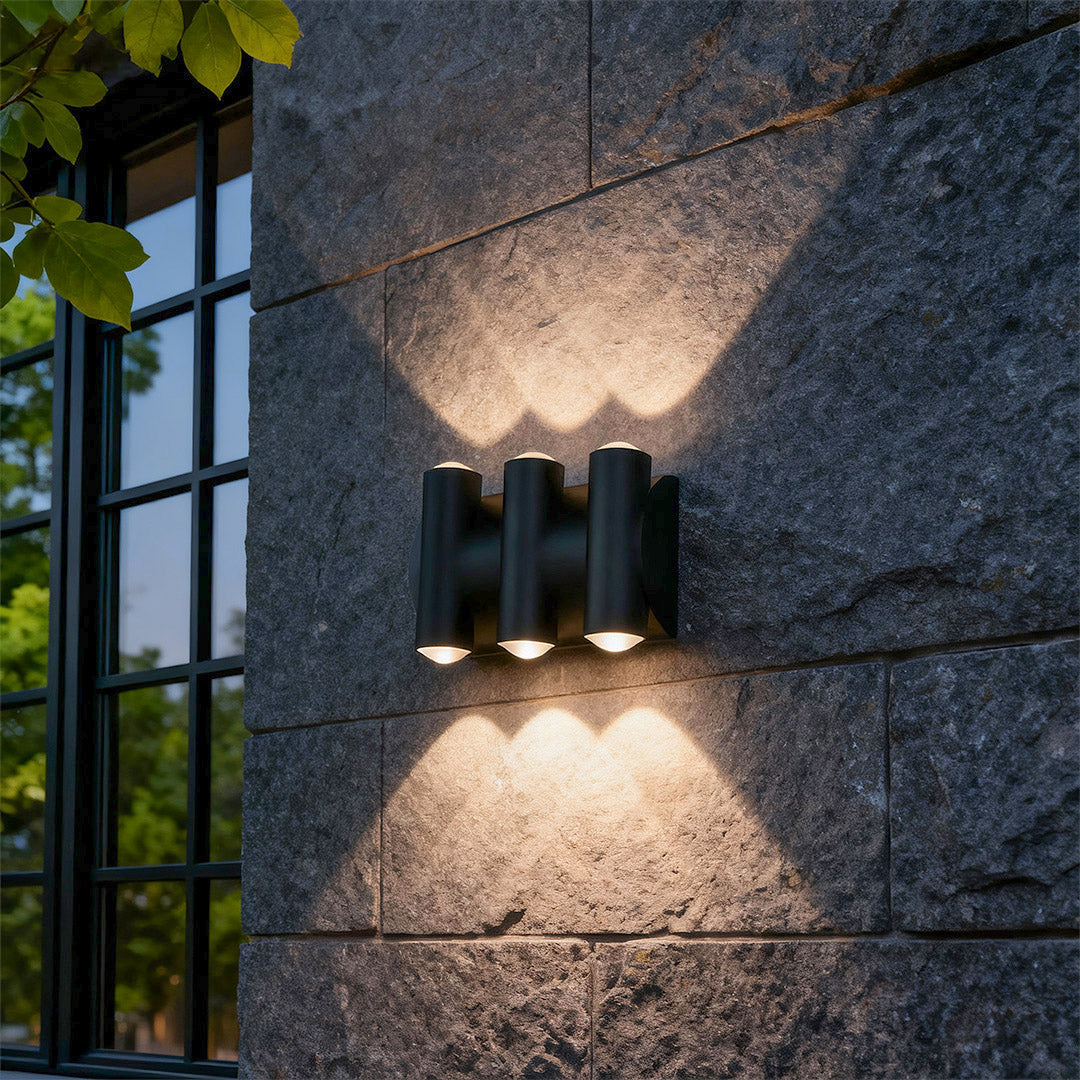 Elegant up down lighting wall lights with glass shade chandelier design illuminating dark textured stone facade with striking light patterns.